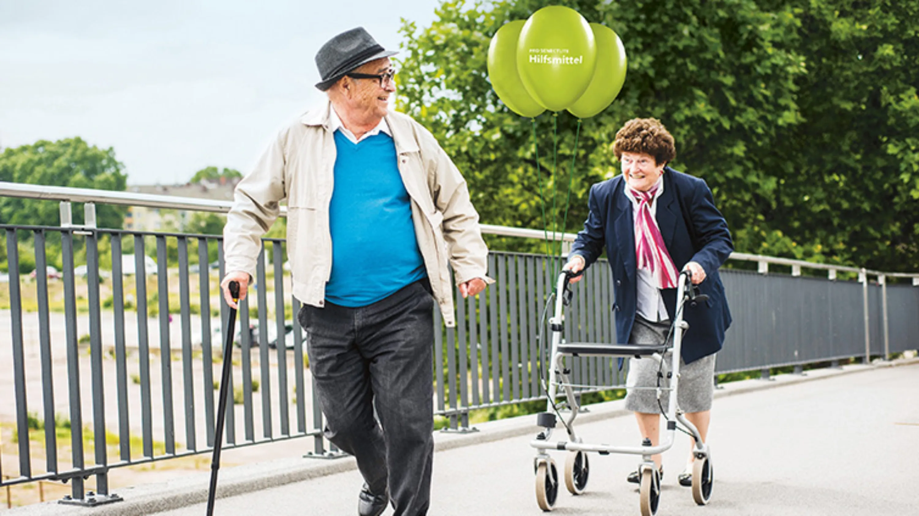 Senior am Gehstock geht mit Seniorin am Rollator spazieren