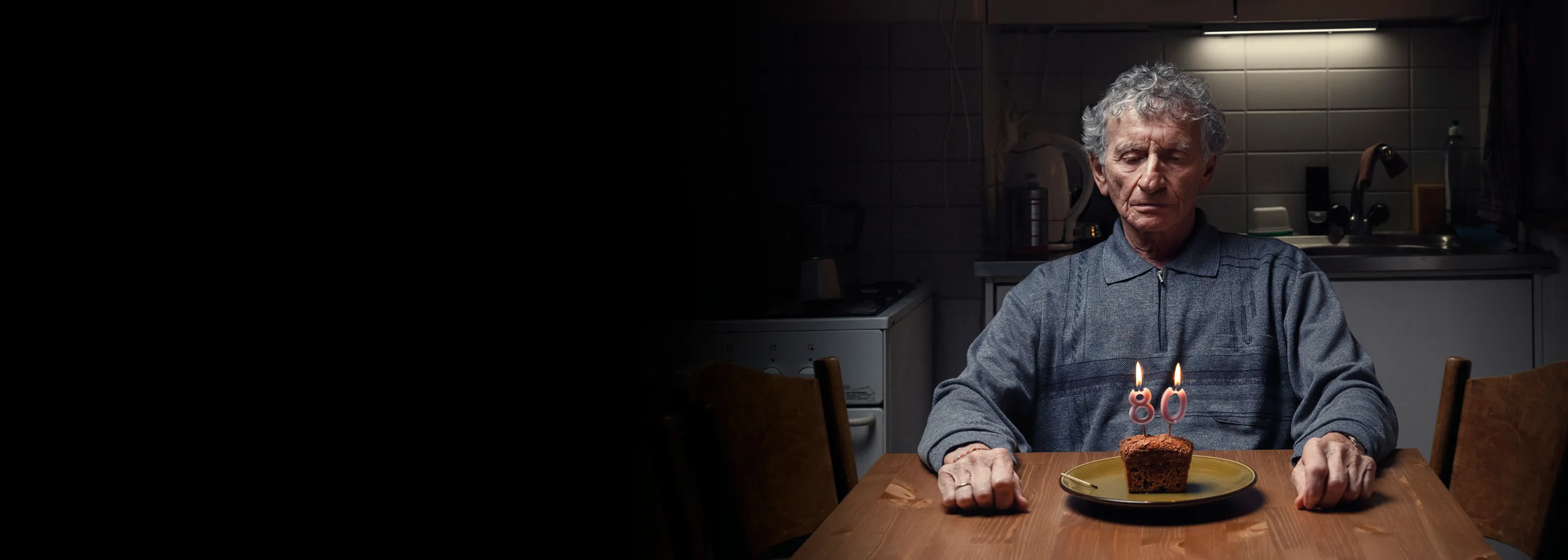 Mann sitzt alleine an einem Tisch vor einem Geburtstagskuchen