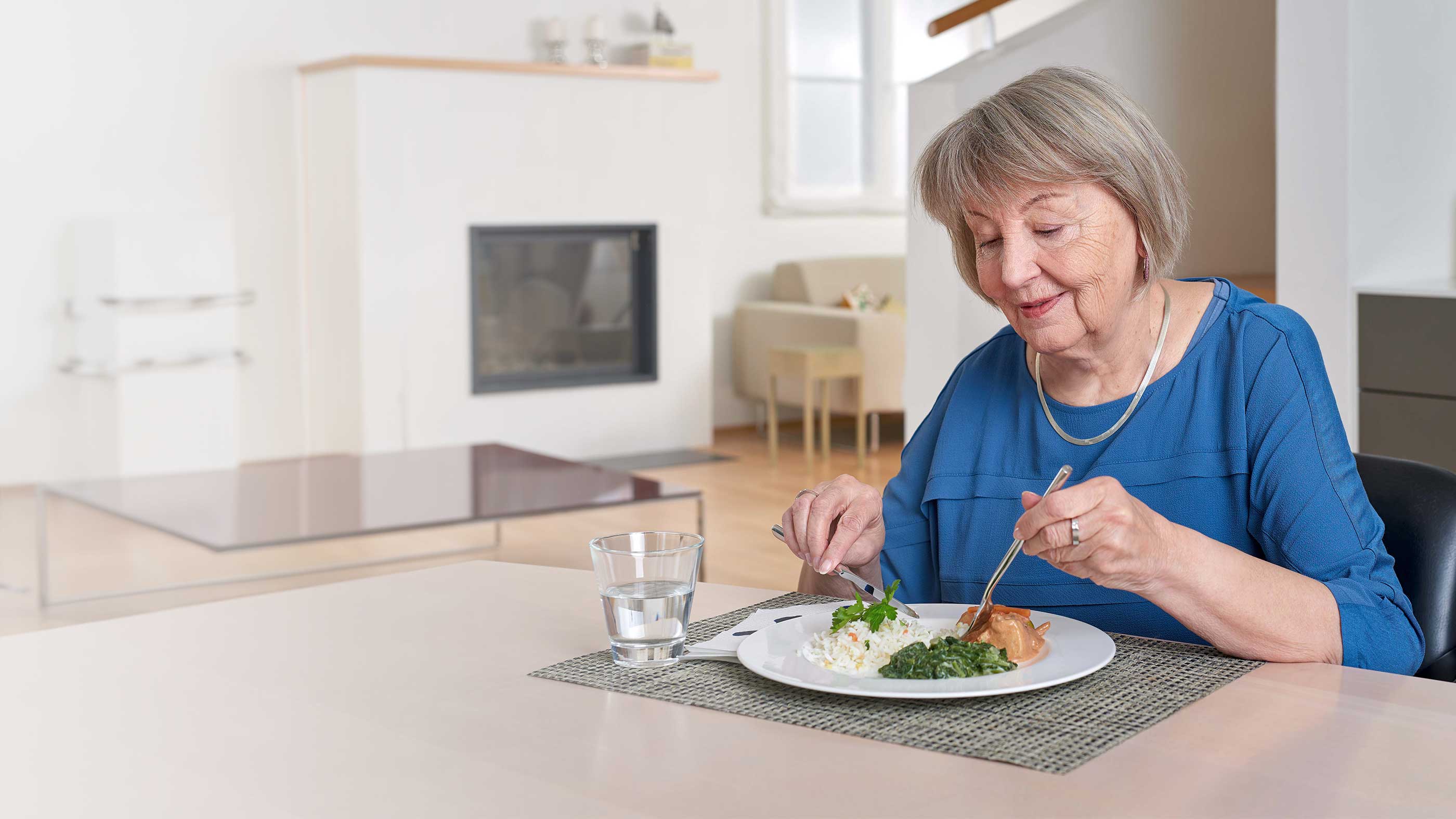 Seniorin sitzt zu Hause an ihrem Esstisch und geniesst ein Mittagessen, welches von der Prosenectute Obwalden gekocht und geliefert wurde.